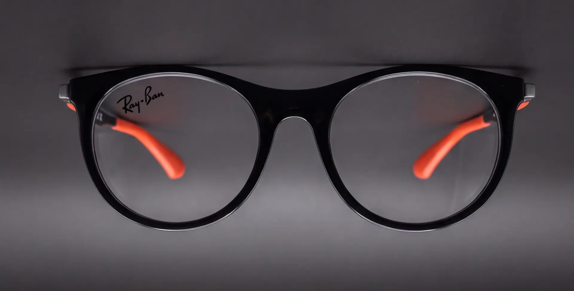Vedere frontală a ramei Ray-Ban pentru copii, negru cu brațe portocalii, ArenaMed Optics