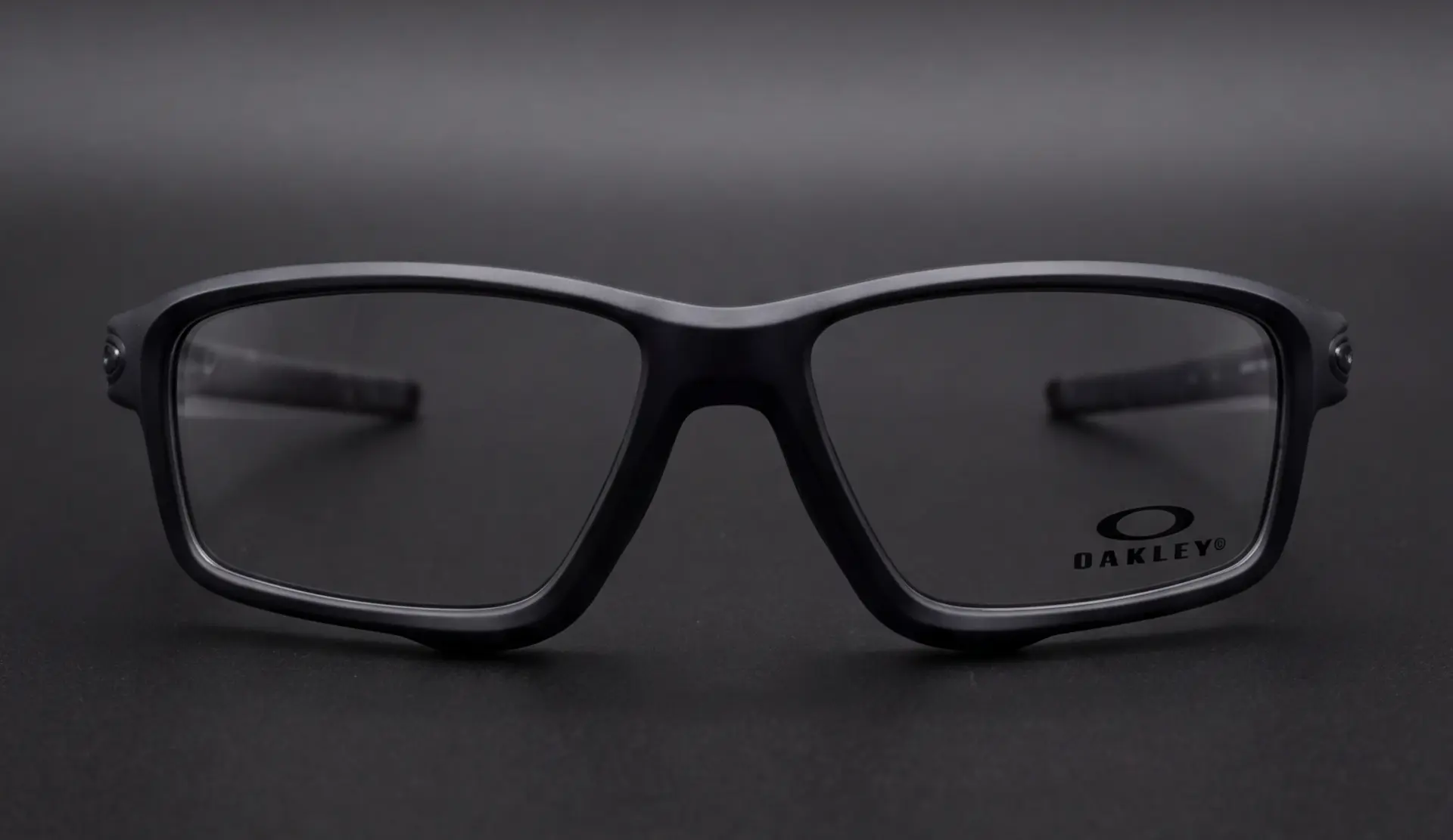 Ramă Oakley Crosslink negru mat, prim-plan frontal cu brațele pliate