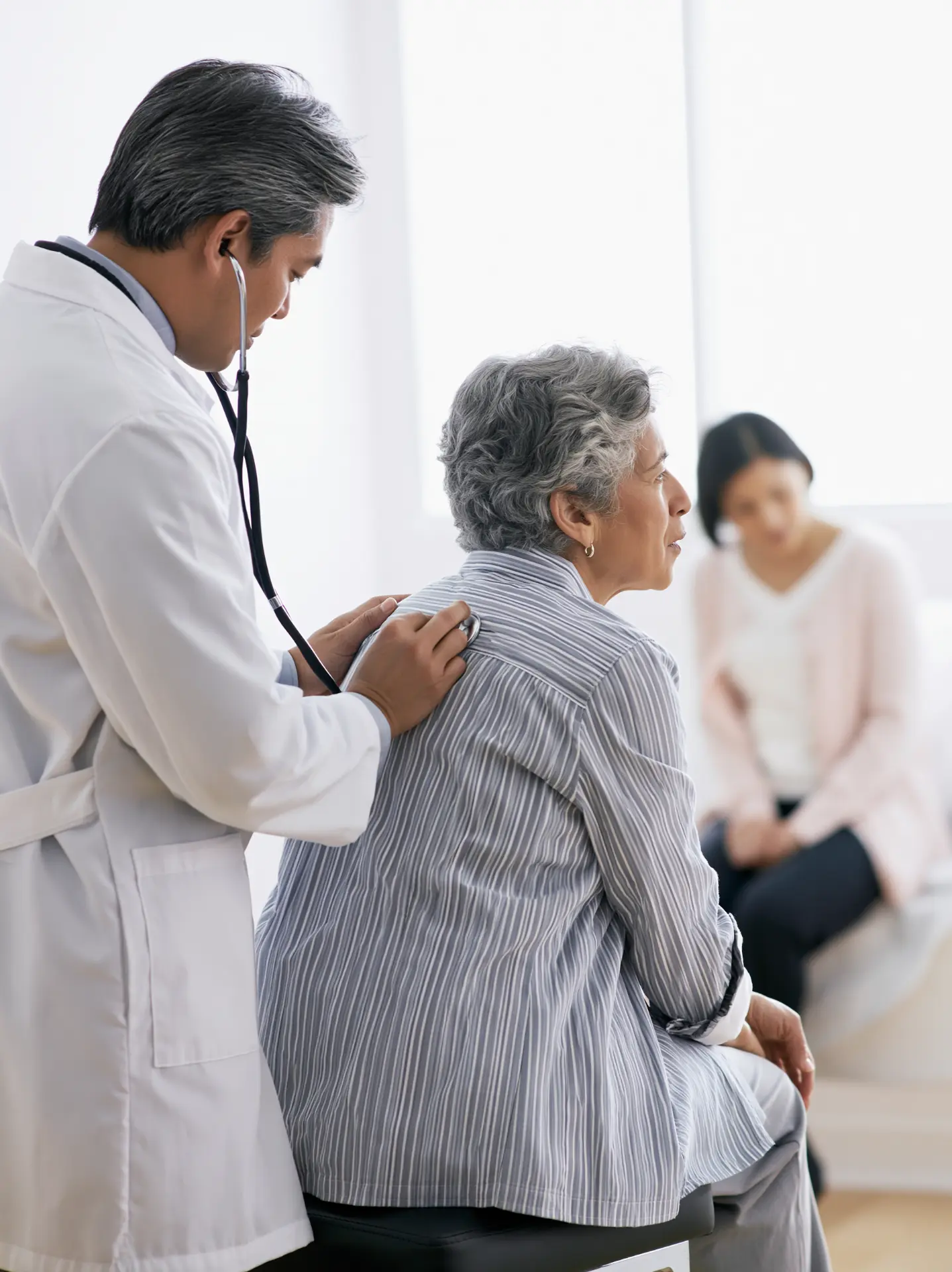 Medic pneumolog ascultând plămânii unei paciente cu stetoscopul