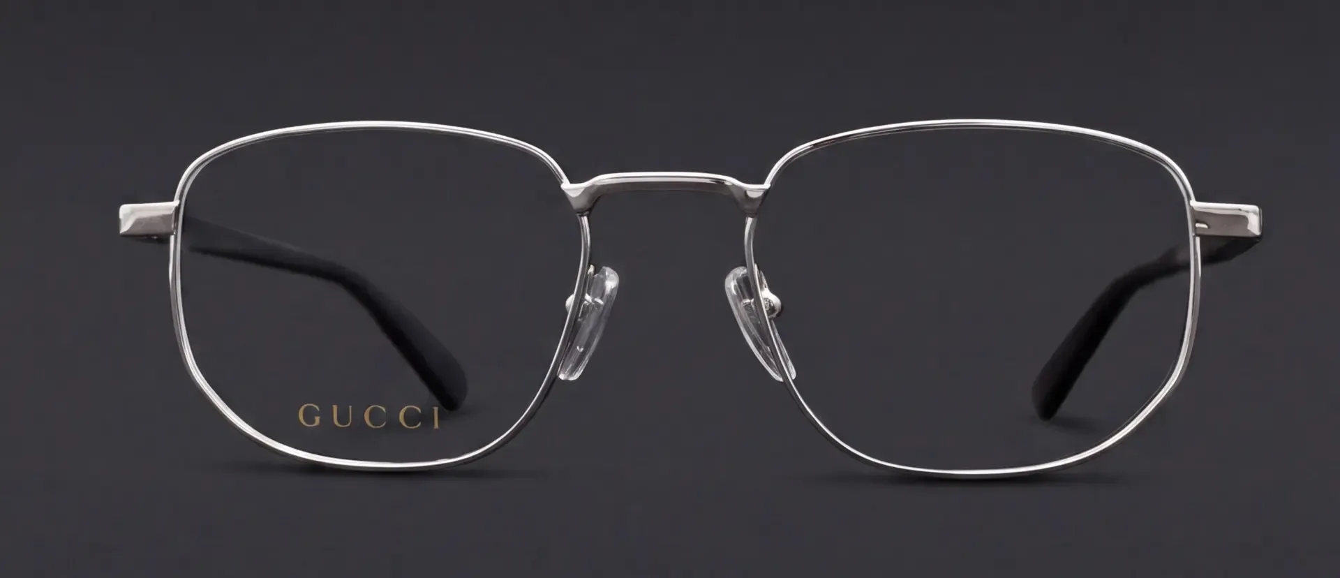 Ramă Gucci metalică argintie, vedere frontală cu logo auriu pe lentilă, disponibilă la ArenaMed Optics