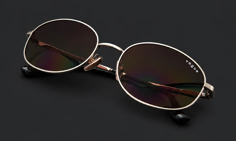 Ramă Vogue ovală aurie pliată, cu logo Vogue pe lentilă, disponibilă la ArenaMed Optics