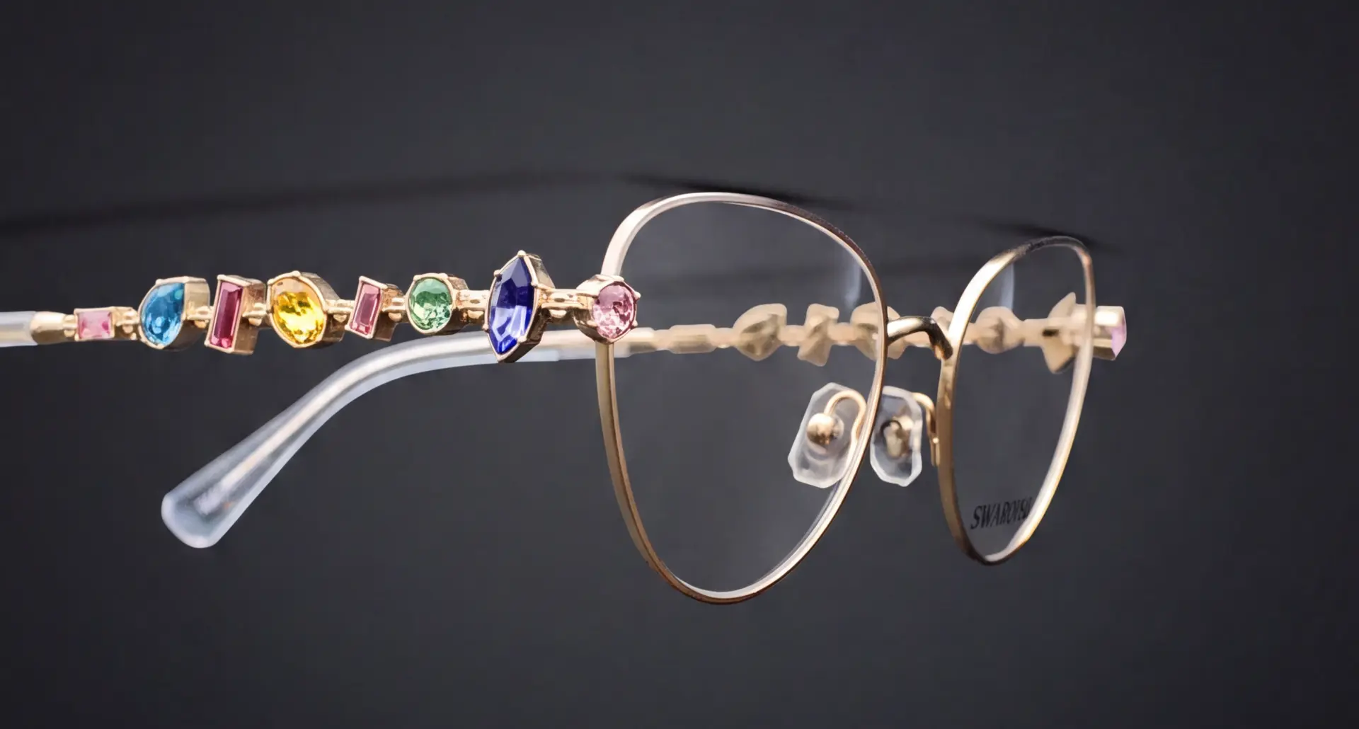 Ramă Swarovski aurie văzută din profil, cu braț decorat cu cristale colorate