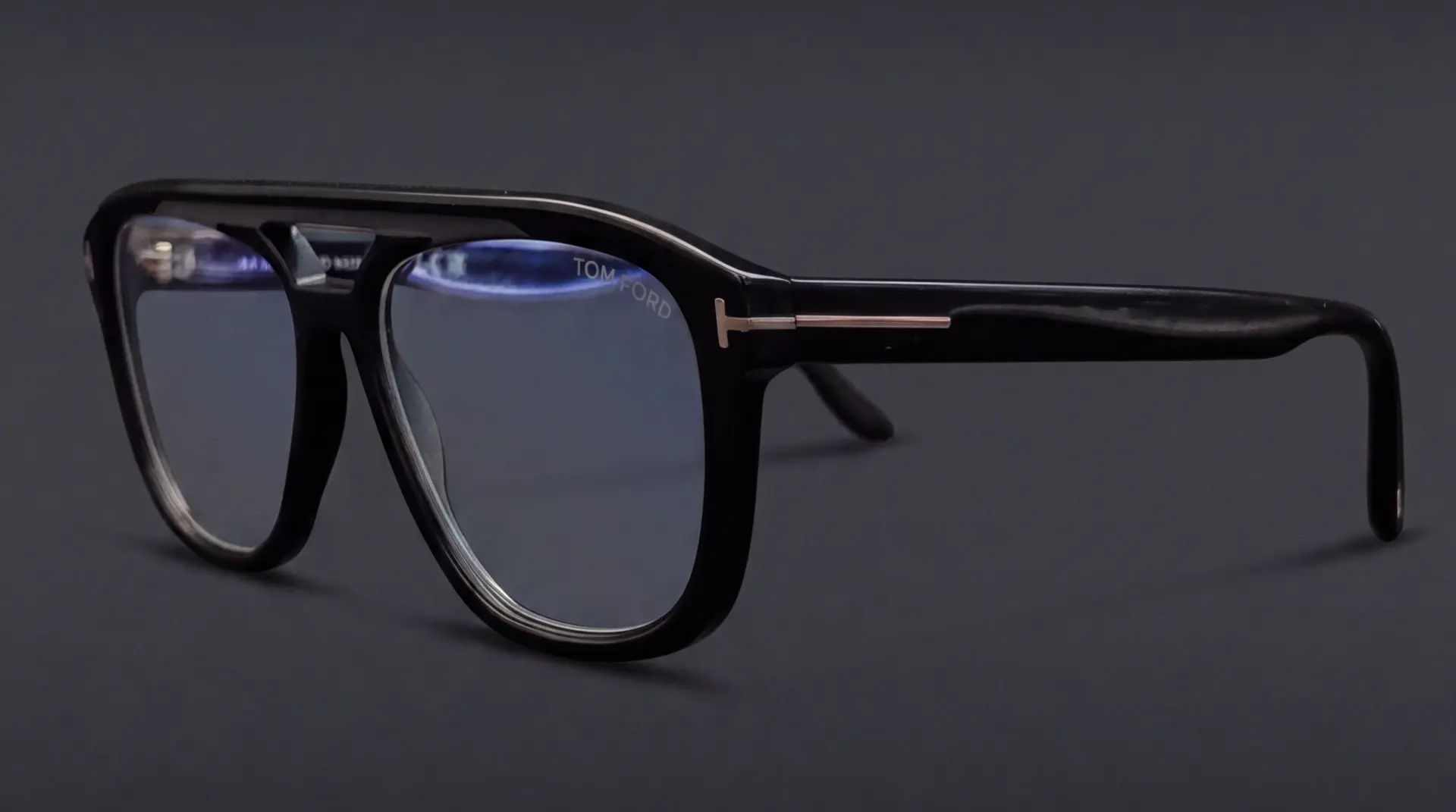 Ramă Tom Ford neagră tip aviator, vedere semi-profil cu logo T auriu pe braț, disponibilă la ArenaMed Optics