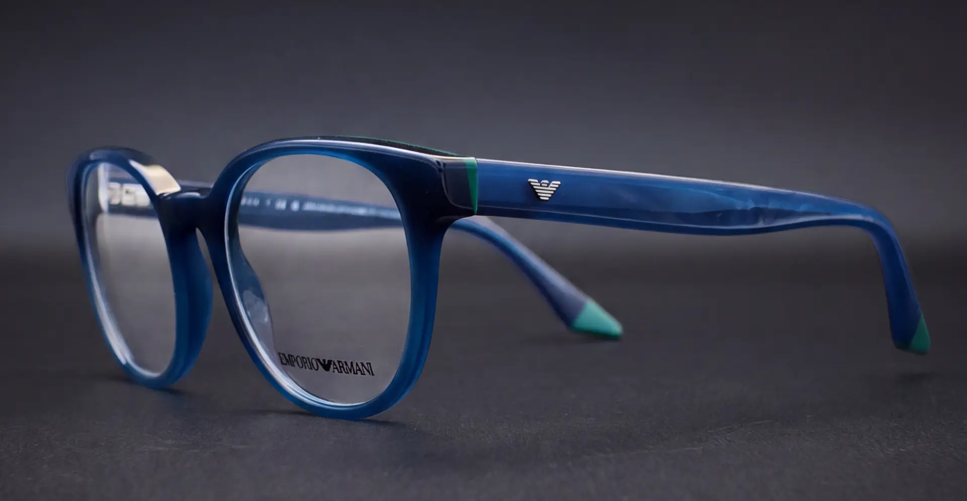 Ramă Emporio Armani pentru copii văzută din profil, braț albastru cu logo